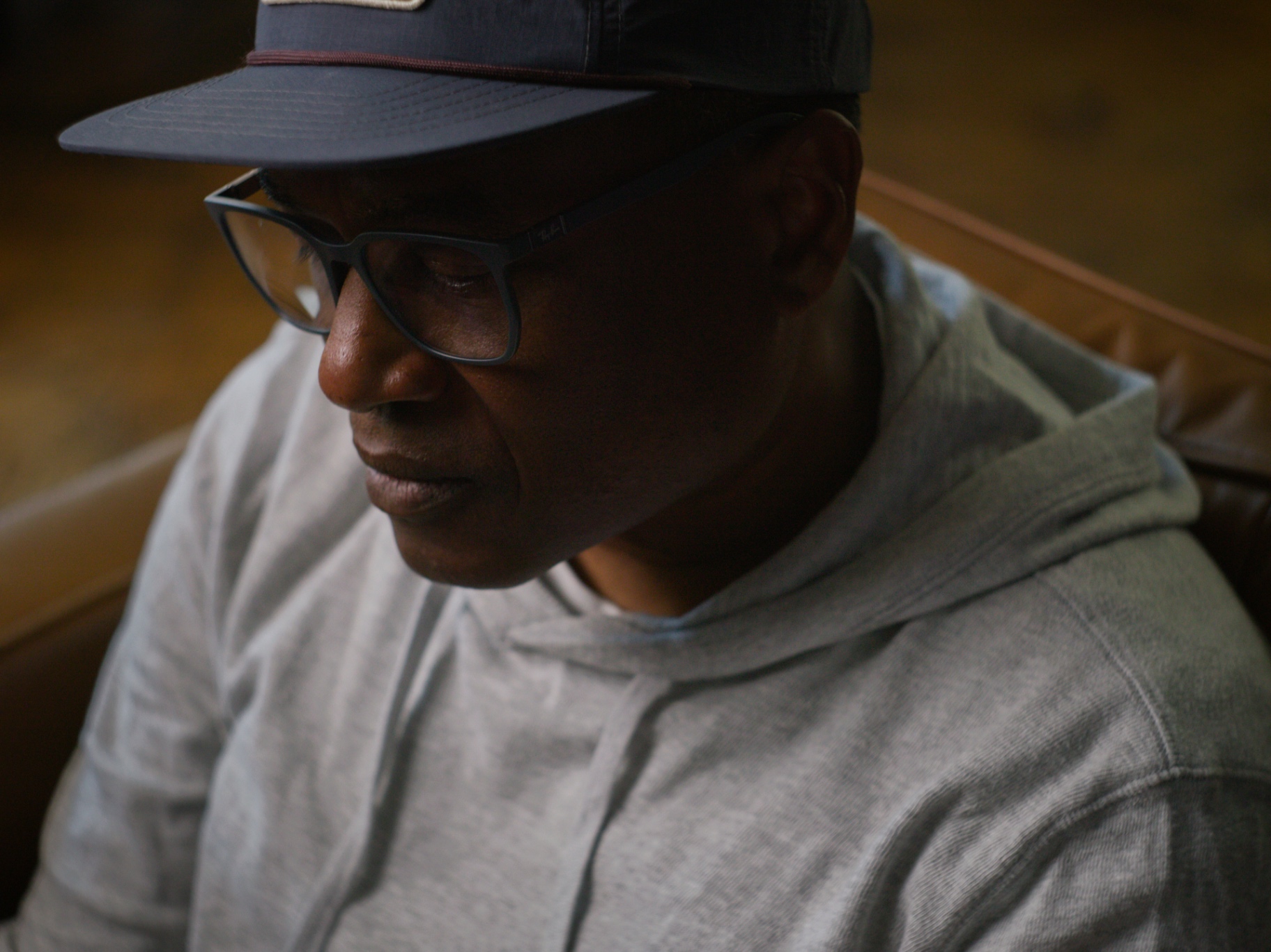 Quiet portrait of Al in cap and glasses, lit by warm interior light