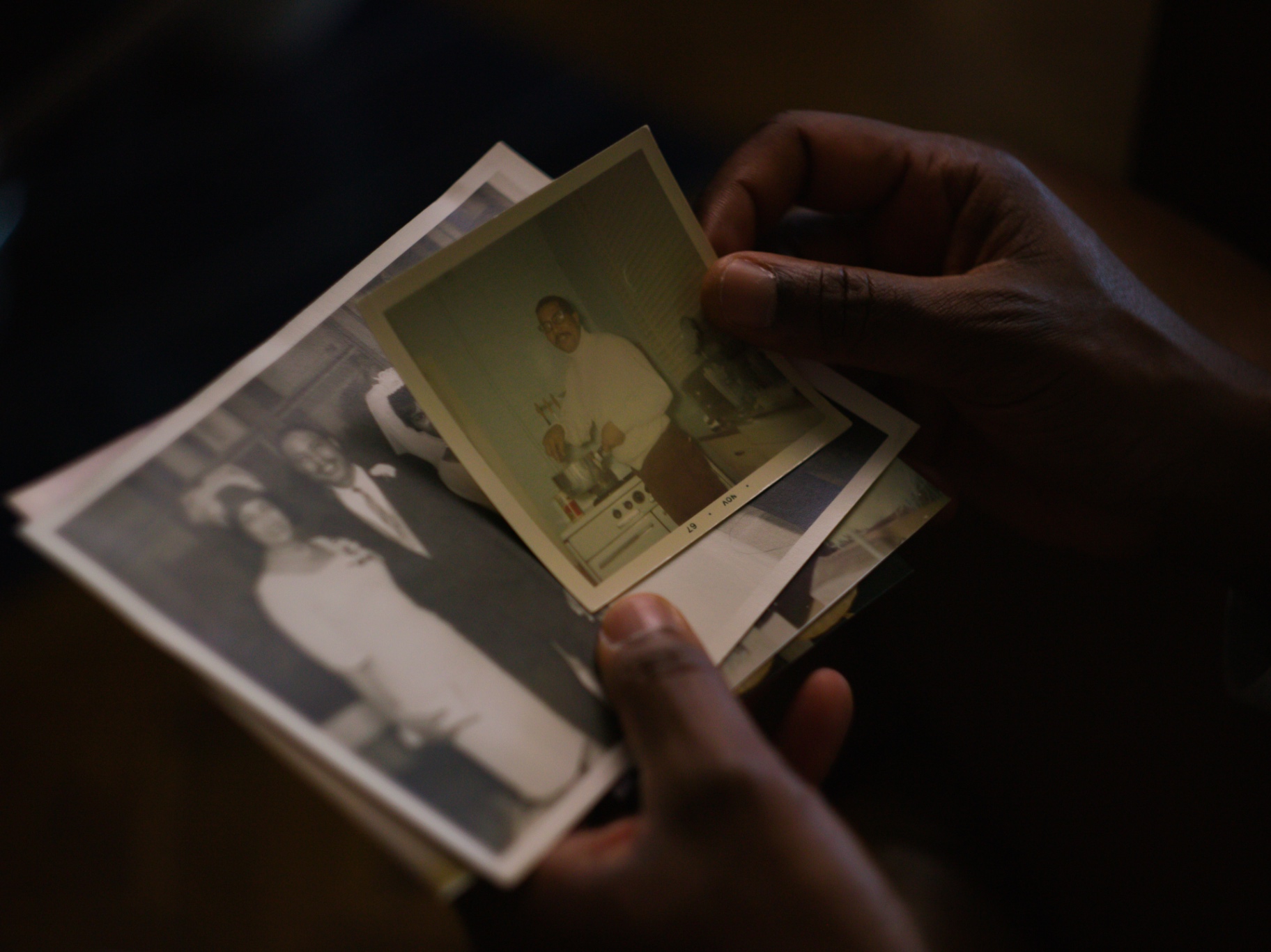 Hands holding a stack of vintage family photographs
