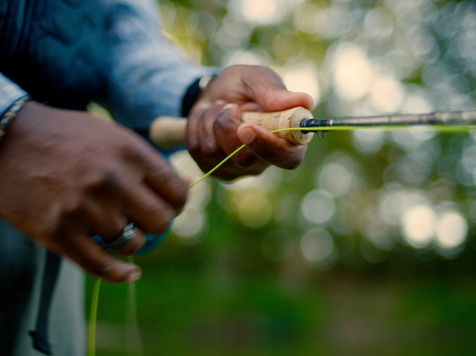 Close-up of hands stripping fly line from a cork-handled rod